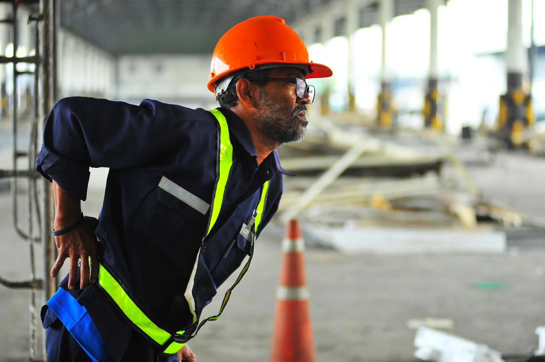 A construction worker at a jobsite holding his back in pain